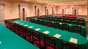 Une salle de conférence avec de longues tables et des chaises, des piliers en pierre et une fresque murale.