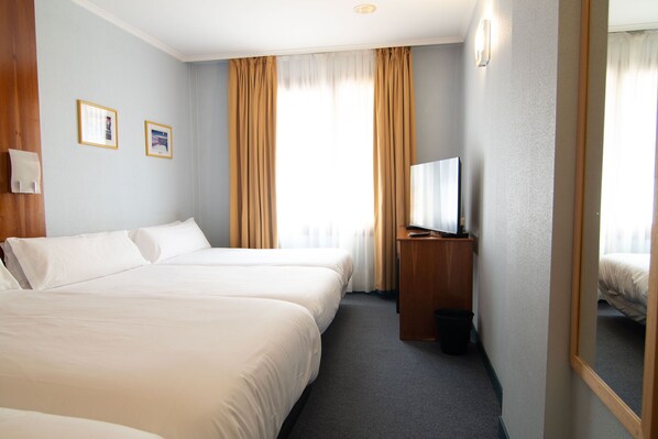 Une chambre d’hôtel avec deux lits, une télévision, une petite table et un miroir.