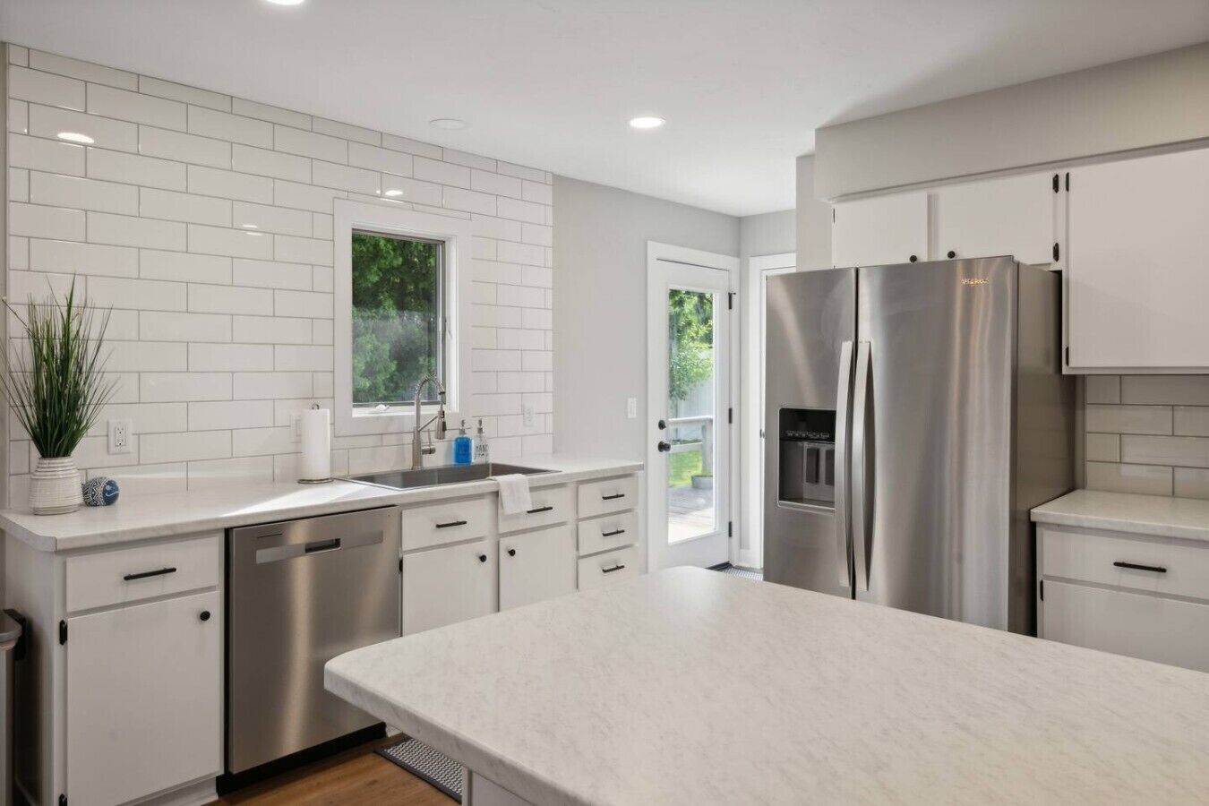 Una cocina moderna con armarios blancos, electrodomésticos de acero inoxidable y una isla grande.