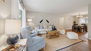Un salon moderne comprenant un canapé, un fauteuil à rayures, une table basse et un coin repas avec une table et des chaises.