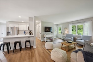 A modern living space with a kitchen, dining area, and seating area with a view.