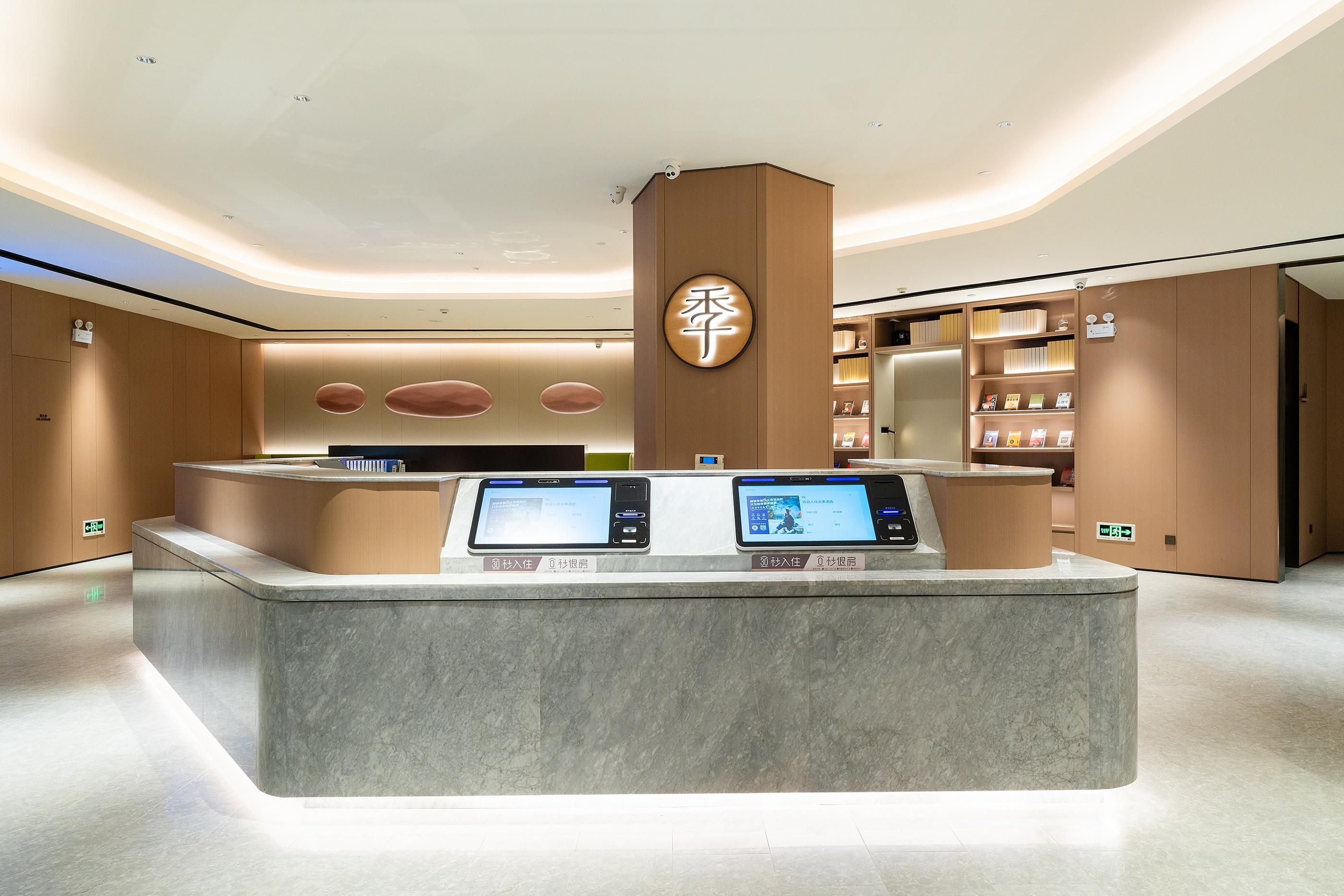 A modern reception desk with digital displays, a wooden accent wall, and a clean, minimalist design.