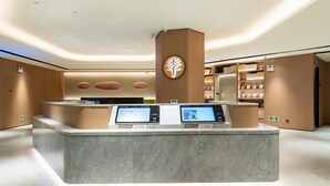 A modern reception desk with digital displays, a wooden accent wall, and a clean, minimalist design. - Ji Hotel Zhuhai Gaolangang Shopping Center (Zhuhai)