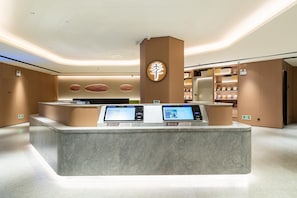 A modern reception desk with digital displays, a wooden accent wall, and a clean, minimalist design. - Ji Hotel Zhuhai Gaolangang Shopping Center (Zhuhai)