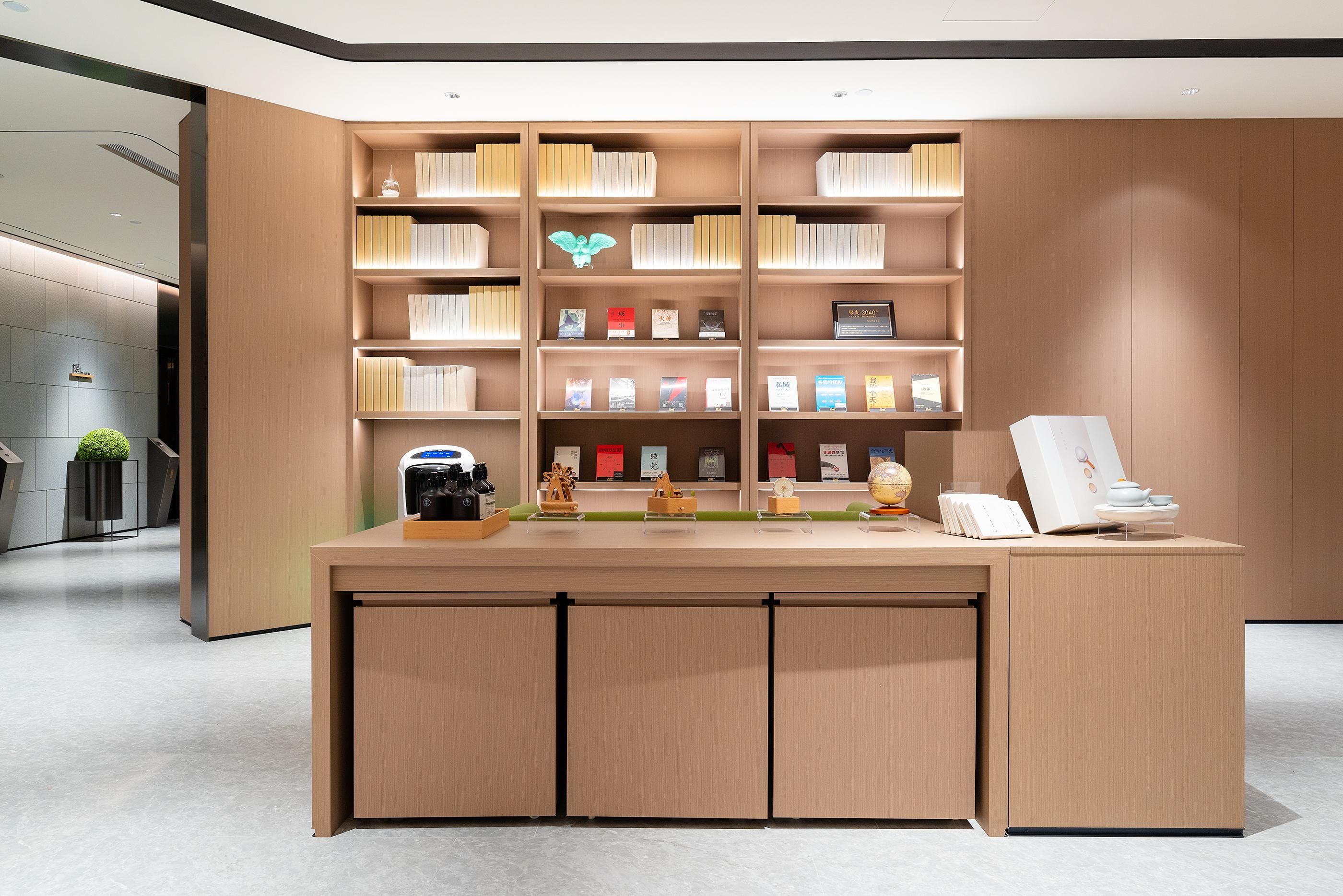 Un mostrador de recepción moderno con acabado de madera, rodeado de estanterías llenas de libros y diversos objetos decorativos.