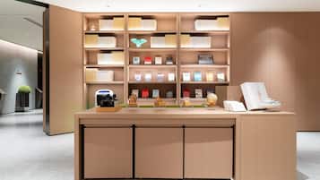 Un mostrador de recepción moderno con acabado de madera, rodeado de estanterías llenas de libros y diversos objetos decorativos.