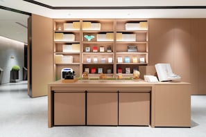 Un comptoir d’accueil moderne, doté d’un revêtement en bois, entouré d’étagères remplies de livres et de divers objets décoratifs.
