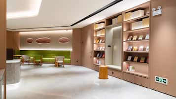 A modern library with bookshelves, seating areas, and a marble floor.