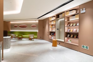 A modern library with bookshelves, seating areas, and a marble floor. - Ji Hotel Zhuhai Gaolangang Shopping Center (Zhuhai)