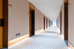 A hotel corridor with a tiled floor, doors on both sides, and a sign indicating an exit. - Ji Hotel Zhuhai Gaolangang Shopping Center (Zhuhai)