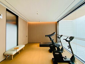 A modern gym with two stationary bikes, a bench, and a wooden wall. - Ji Hotel Zhuhai Gaolangang Shopping Center (Zhuhai)