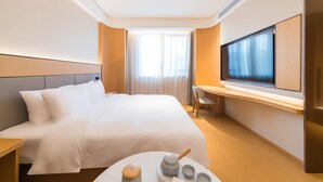 A hotel room with a large bed, a desk with a chair, a television, and a small table with a teapot and cups. - Ji Hotel Zhuhai Gaolangang Shopping Center (Zhuhai)