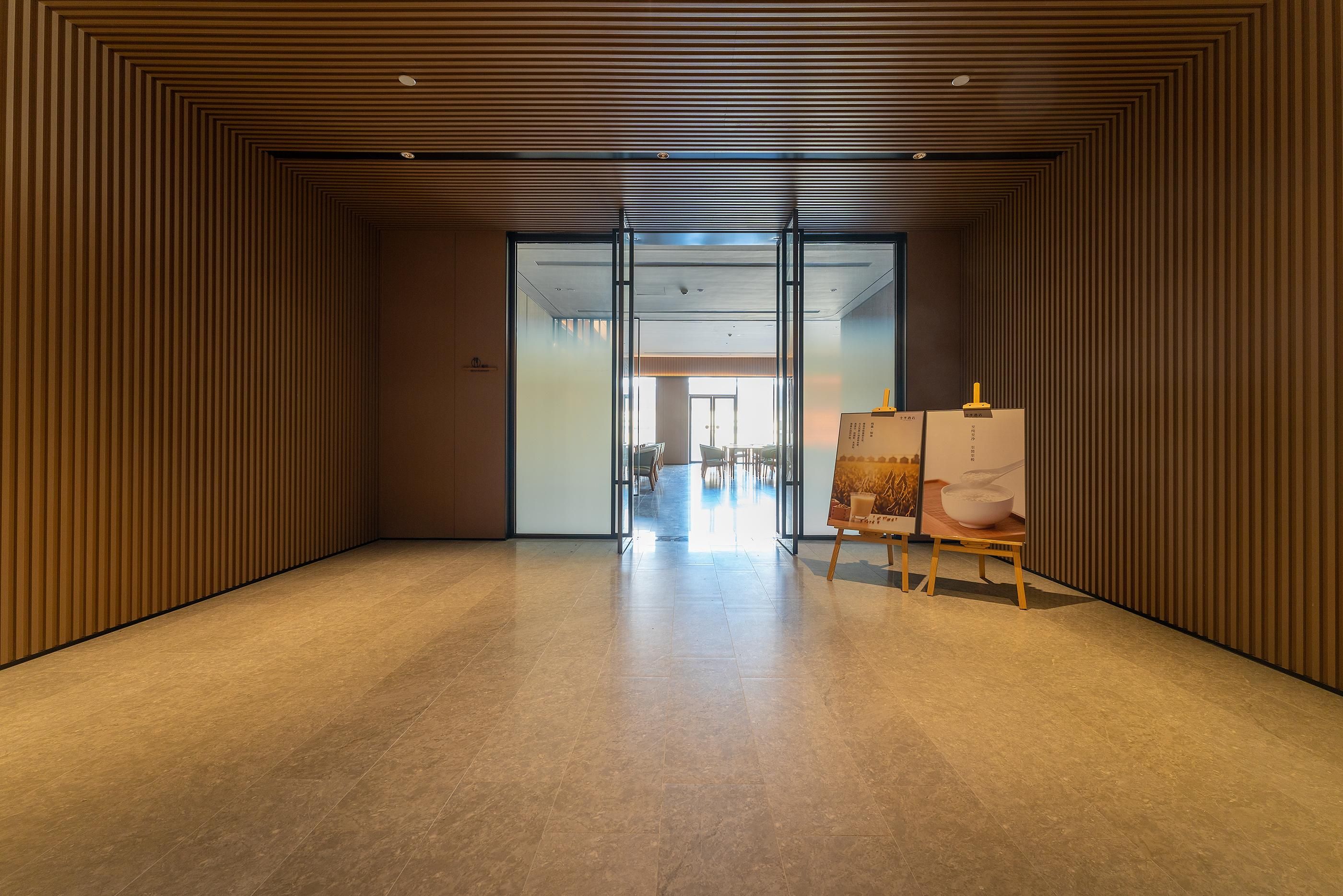 Un interior moderno con un panel de madera en la pared, un vidrio que conduce a un comedor y un cuadro sobre caballete.