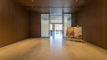 Un interior moderno con un panel de madera en la pared, un vidrio que conduce a un comedor y un cuadro sobre caballete.