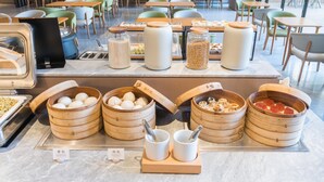A buffet area with various food items, including dumplings and rice bowls, in a modern dining setting with green chairs and tables. - Ji Hotel Zhuhai Gaolangang Shopping Center (Zhuhai)