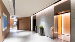 A modern hotel lobby with a polished floor, a reception desk, and a wall-mounted plant. - Ji Hotel Zhuhai Gaolangang Shopping Center (Zhuhai)