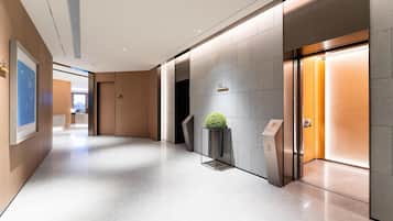 A modern hotel lobby with a polished floor, a reception desk, and a wall-mounted plant.