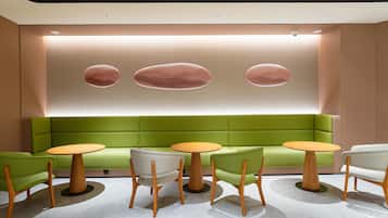 A modern interior with a green sofa, wooden chairs, and a round table.