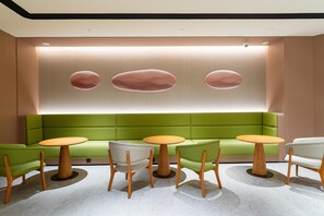 A modern interior with a green sofa, wooden chairs, and a round table. - Ji Hotel Zhuhai Gaolangang Shopping Center (Zhuhai)
