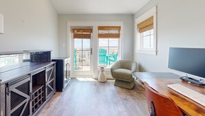 A modern living room with a wooden coffee table, a sofa, a TV, and a large window with blinds. - Private Pool, Golf Cart Included, Parking for 4 (Port Aransas)