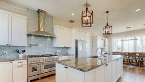 A spacious kitchen with white cabinetry, a large island, stainless steel appliances, and a blue-tiled backsplash. - Private Pool, Golf Cart Included, Parking for 4 (Port Aransas)