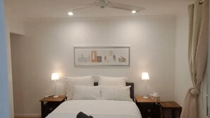 A hotel room with a bed, two bedside tables, a ceiling fan, and a wall-mounted artwork. - Private guest suite @ Sorrento (Bundall)