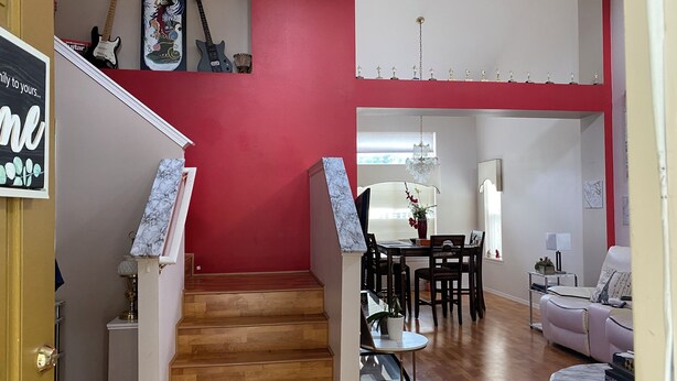 A staircase leading to a dining area with a red wall, a chandelier, and a dining table with chairs. - CALM Guest House (Auburn)