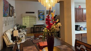 A dining area with a chandelier, a vase with flowers, and a dining table with placemats. - CALM Guest House (Auburn)