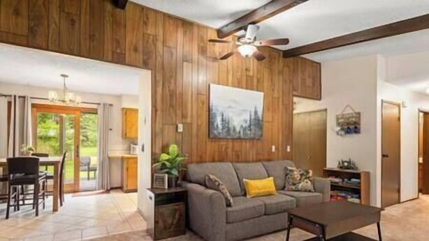 A living room with a wooden ceiling, a gray sofa, a coffee table, and a painting on the wall. - Cedar Trees Retreat (Sandpoint)