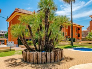 Un bâtiment doté d’un toit en tuiles, entouré de palmiers et agrémenté d’une piscine.
