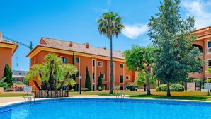 A swimming pool with a clear blue water surface, surrounded by a well-maintained garden with various trees and shrubs.