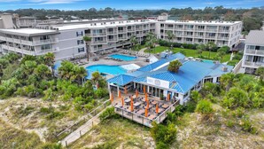 A hotel with multiple floors, a pool area, and outdoor seating. - Beachfront Condo w Ocean Views and Pool (Tybee Island)
