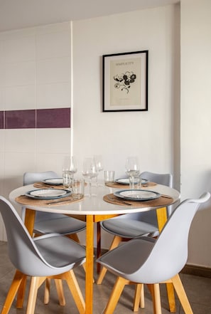 A dining area with a round table set for four, surrounded by grey chairs with wooden legs. - Apartamento inteiro a 3 minutos da Praia de Gandia (Gandia)