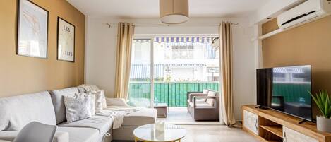 A living room with a sofa, a coffee table, a TV, and a balcony with a view.