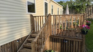 Una terraza de madera con una escalera que conduce a un porche cubierto.