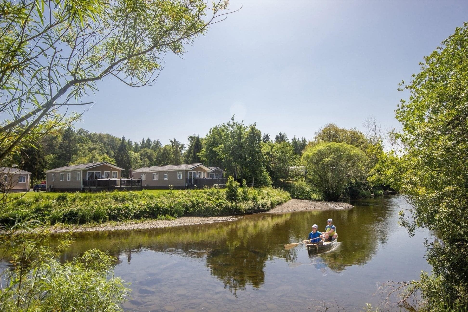 A river with a rowboat and houses on the bank.