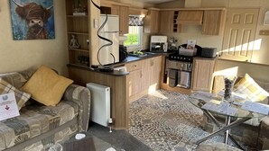 Un espacio habitable compacto con kitchenette, un sofá, una mesa de centro y un cuadro.