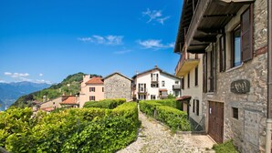 A cobblestone street in a hillside village with stone buildings and lush greenery. - Angelina: Panoramic Lake View House on Monte Brè | Terrace & Balcony, Lugano, Switzerland (Lugano)