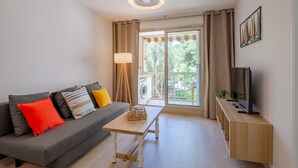 Un salon moderne avec un canapé gris, une table basse en bois et un téléviseur posé sur un meuble en bois.