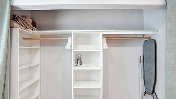 A walk-in closet with open shelves, a hanging rod, and a shoe rack.