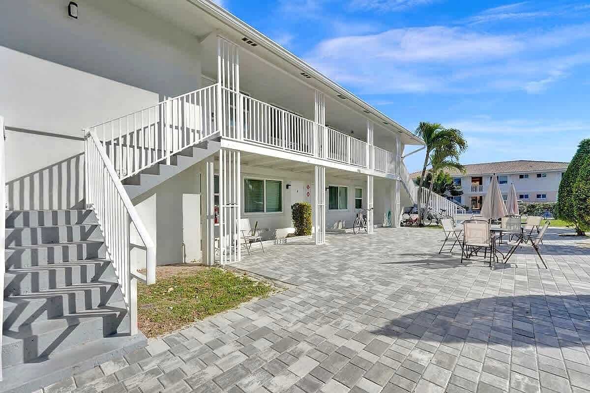 A two-story building with a covered outdoor area, a staircase, and a patio with outdoor furniture.