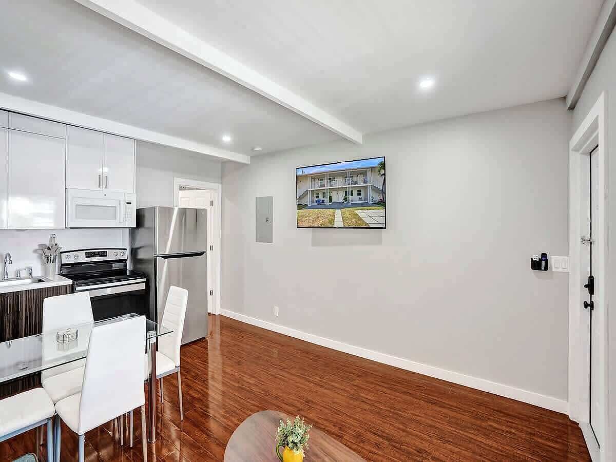 A modern kitchen with white cabinets, stainless steel appliances, and a dining area with white chairs.