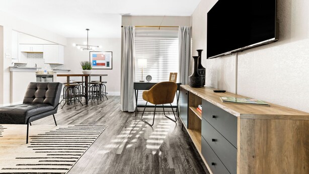 A modern living room with a sofa, a wooden coffee table, and a TV mounted on the wall. - Walk to Globe Life Field & AT&T Stadium - Free Parking - 2BR Sleeps 6 (Arlington)