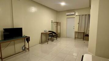 Une chambre d’hôtel comprenant un lit, un bureau avec une télévision, une chaise, une petite table avec une tasse et un luminaire suspendu.