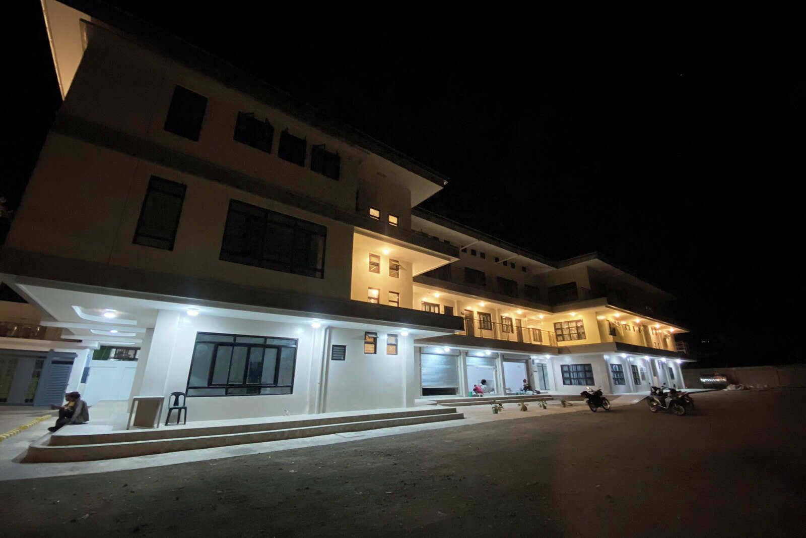 A multi-story hotel with illuminated ground floor windows and a well-lit entrance.