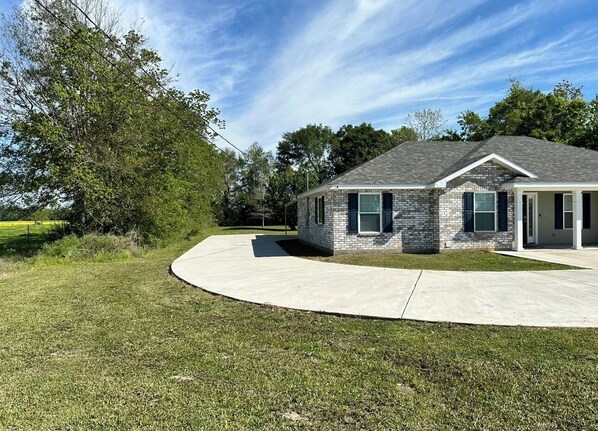 A modern two-story house with a stone facade, a covered patio, and a well-maintained lawn.