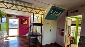 A room with a wooden floor, a staircase, a door with a 'No Smoking' sign, and a fire extinguisher. - Star Guesthouse (Proserpine)