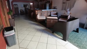 A spacious room with a tiled floor, wicker furniture, a bar area, and a ceiling fan. - Hotel Cabinas Jacomar (Jacó)