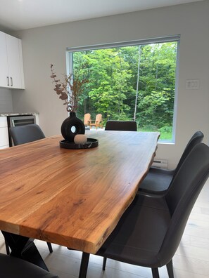 A modern kitchen with a large wooden table, black chairs, and a vase with dried plants. - Zenergie-Orford • Hiking • Cycling • Skiing (Eastman)
