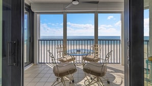 Ein Balkon mit Tisch und Stühlen mit Blick auf einen Strand und das Meer.